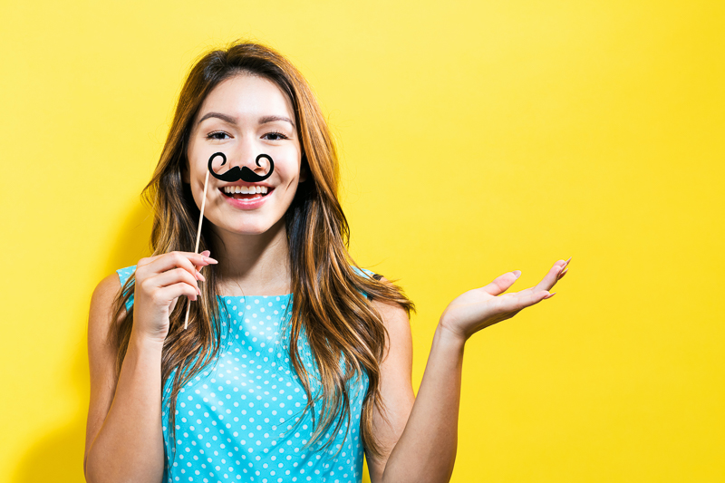 Young woman holding paper party sticks on a yellow background